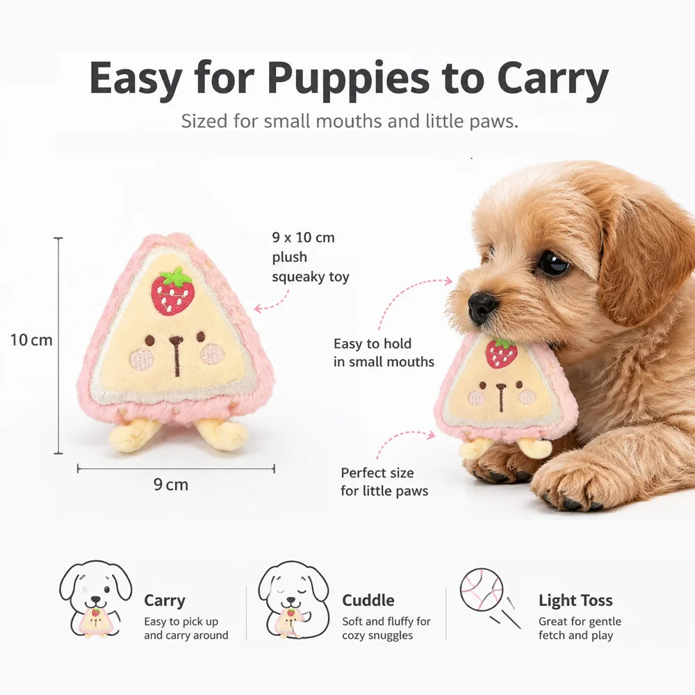 A golden retriever puppy is holding a pink plush food-shaped squeaky toy designed for small mouths and paws.