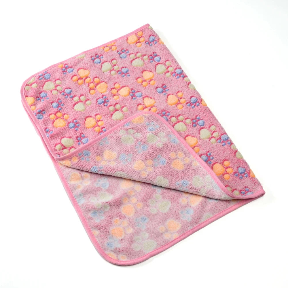 A pink fleece pet blanket featuring a paw print pattern with orange and blue accents.