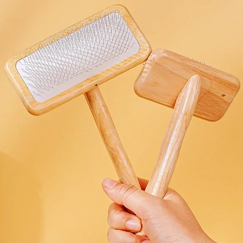 A hand holds a wooden pet grooming brush with massage bristles, showing the flat brush and handle.