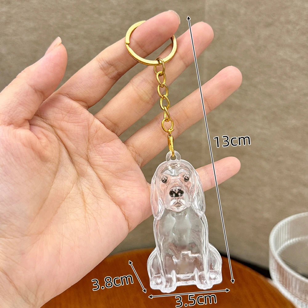 A clear glass puppy-shaped pet hair keepsake keychain is held in a hand, showing its size and detail.