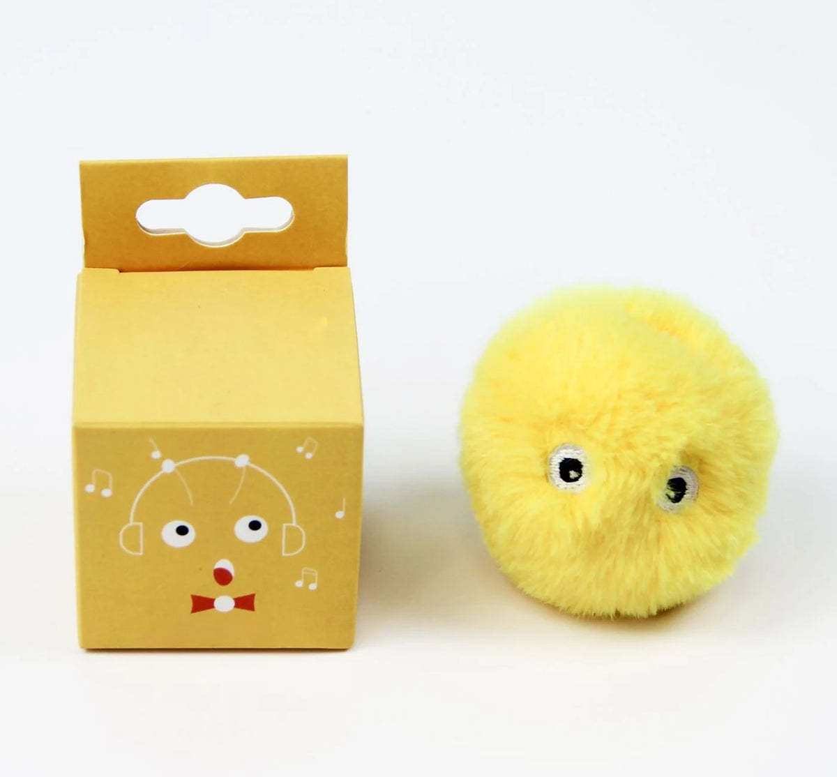 Une boîte en carton jaune avec une découpe, à côté d'une balle de peluche jaune et moelleuse.