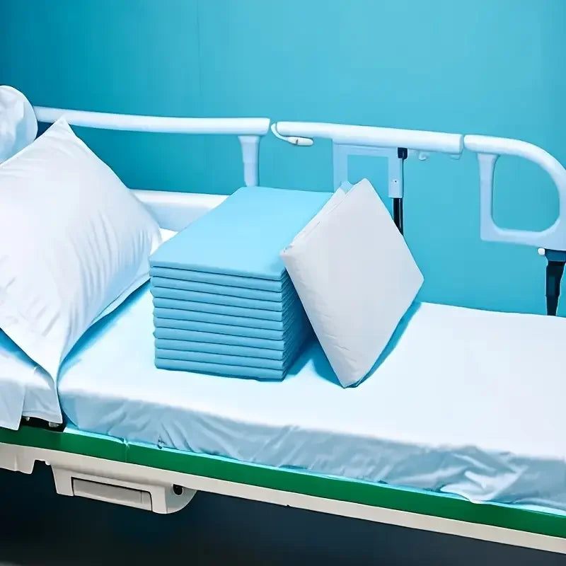A white pillow and blue pads are placed on a hospital bed with a light blue wall background.