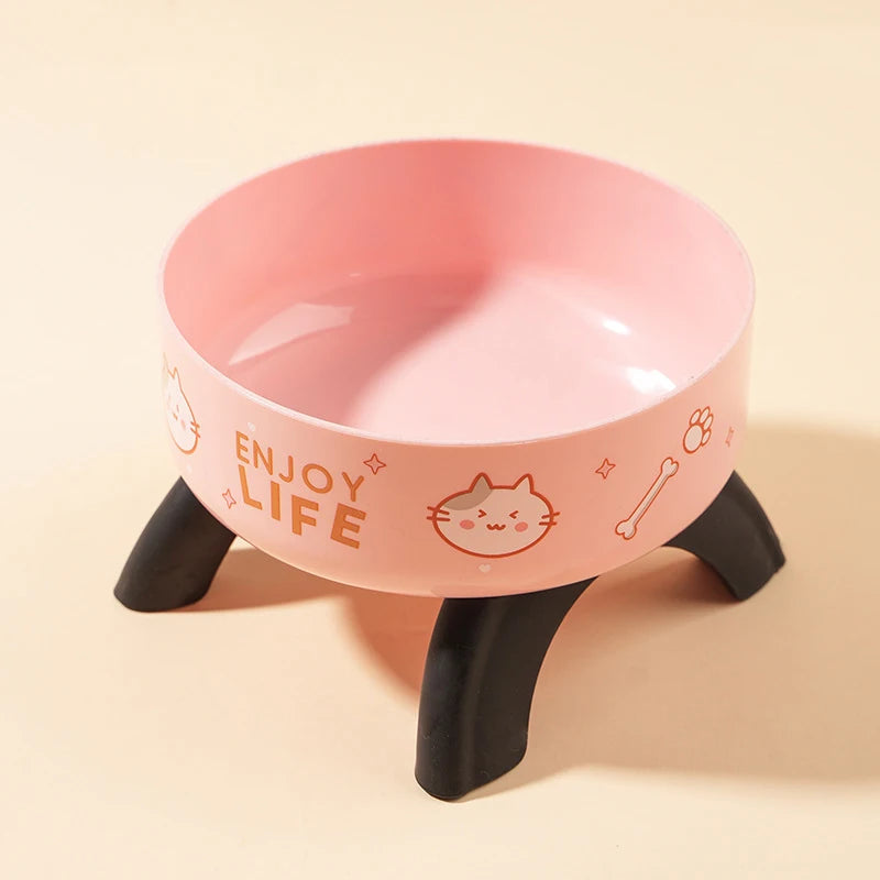 A pink stainless steel pet food bowl with a black stand and a cat face design.