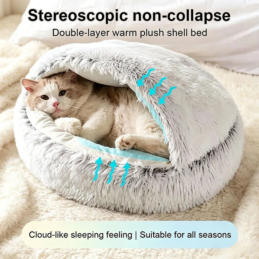 A fluffy, double-layer warm plush shell bed for a cat is shown nestled in a soft, cream-colored blanket.