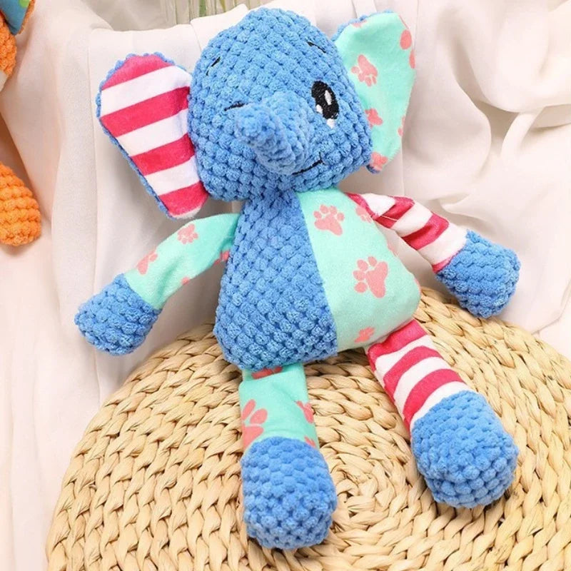 A blue elephant plush toy with pink accents sitting on a woven mat.