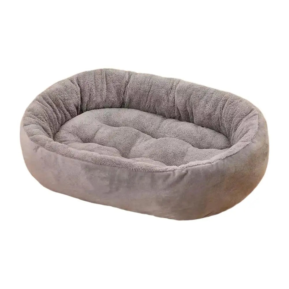 A plush, oval pet bed with a raised rim in a soft gray color.