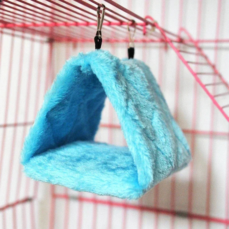 A bright blue plush hanging bird hammock and nest is suspended from a wire rack.