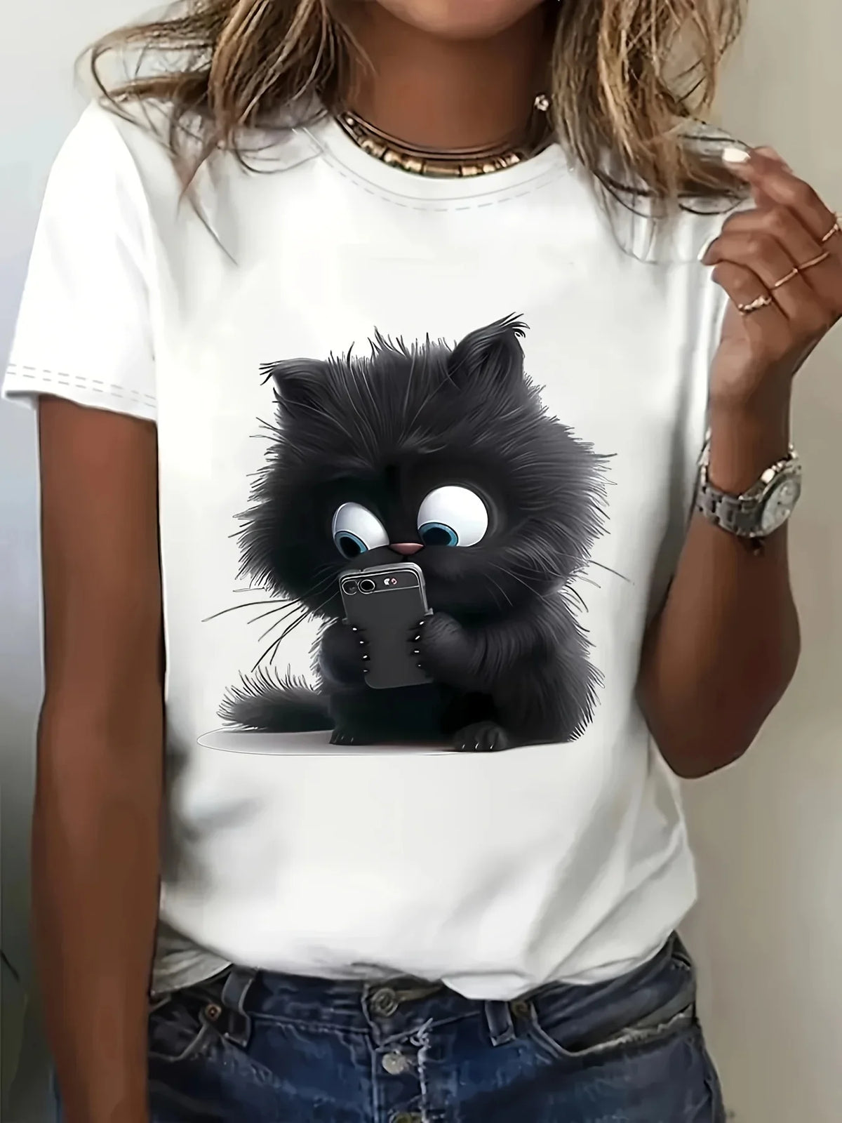 Une femme portant un t-shirt blanc à imprimé de chat cartoon noir, avec un chat noir duveteux regardant l'objectif.