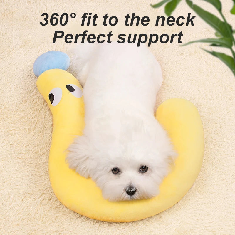 Un perro blanco descansando cómodamente en un cojín de cuello en forma de U amarillo con acento azul.