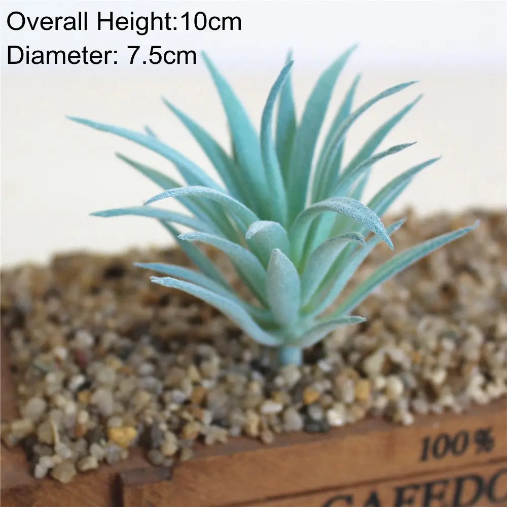 A small, blue artificial succulent plant with spiky leaves planted in a natural gravel substrate.