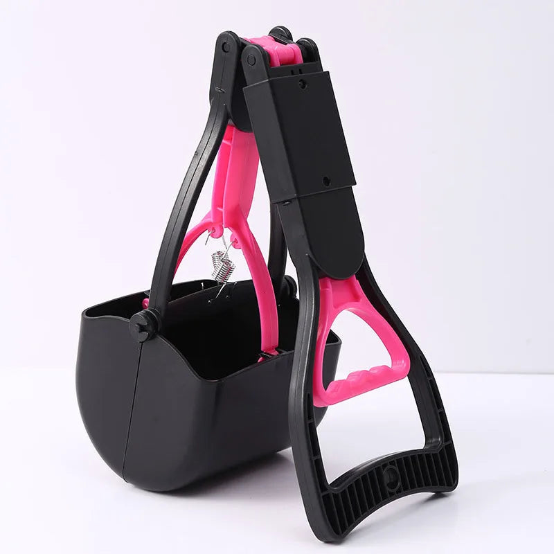 A black and pink foldable pet poop scooper with a handle and container is shown on a white surface.