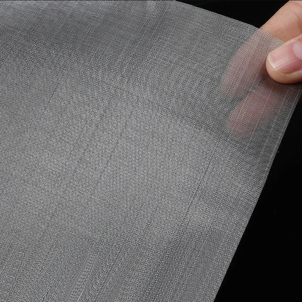 Close-up of a gray stainless steel ant farm escape net being held by a hand.