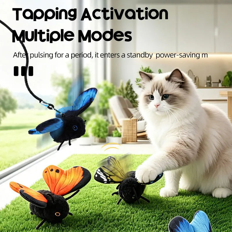 A fluffy white cat interacts with a black motion-activated butterfly toy on green grass.