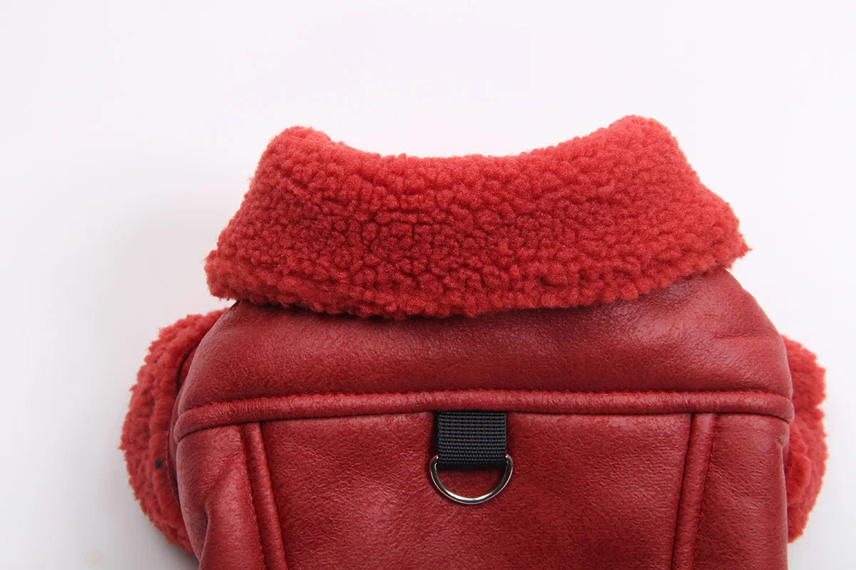 A maroon faux leather dog coat with a thick, fluffy red fleece lining and a black buckle detail.