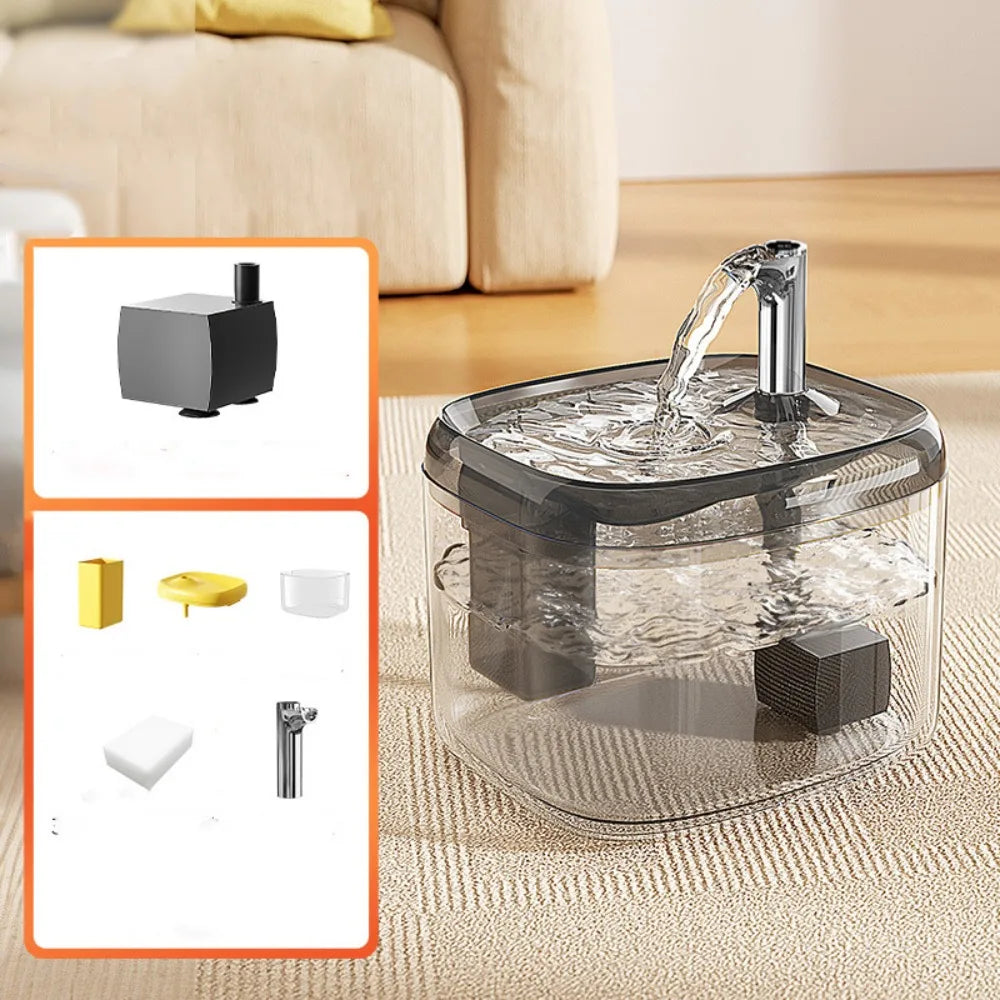 A clear pet drinking fountain with a metal spout is shown on a beige fabric surface.