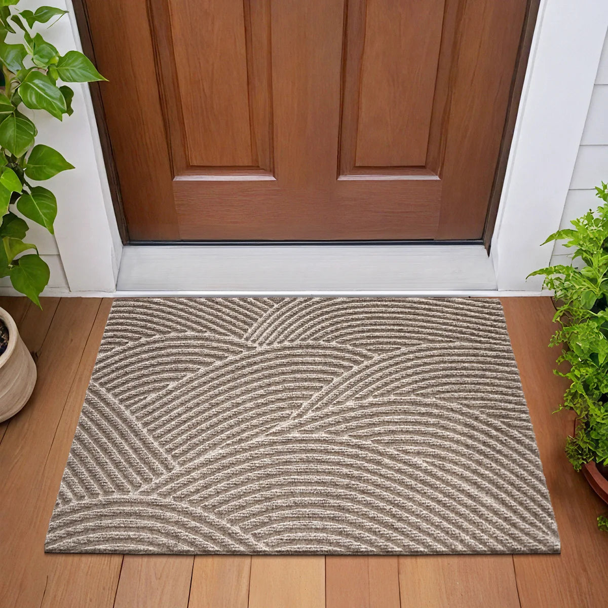 A rectangular gray geometric doormat with wavy lines placed on a wooden floor in front of a brown door.