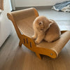 A fluffy orange kitten is resting on a wooden cat scratcher pad designed as a multifunctional sleeping bed.