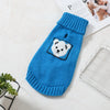 A bright blue knitted sweater for a dog featuring a white bear face design.