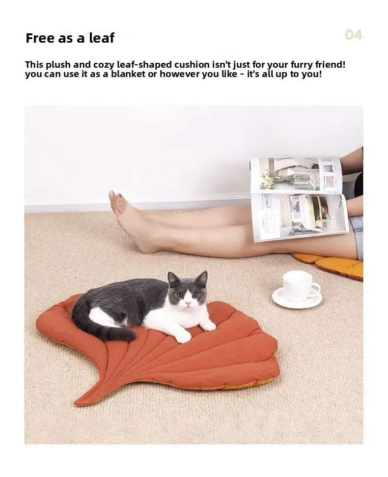 A black and white cat is relaxing on an orange leaf-shaped cushion on a beige carpet.