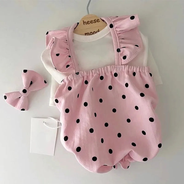 A pink cotton dress with black polka dots displayed on a hanger against a white background.