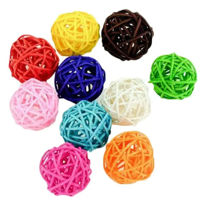 A collection of colorful natural rattan chewing balls for parrots in various shades including yellow, red, purple, green, and