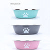 A three-piece set of stainless steel pet bowls in teal, gray, and pink with white paw prints.
