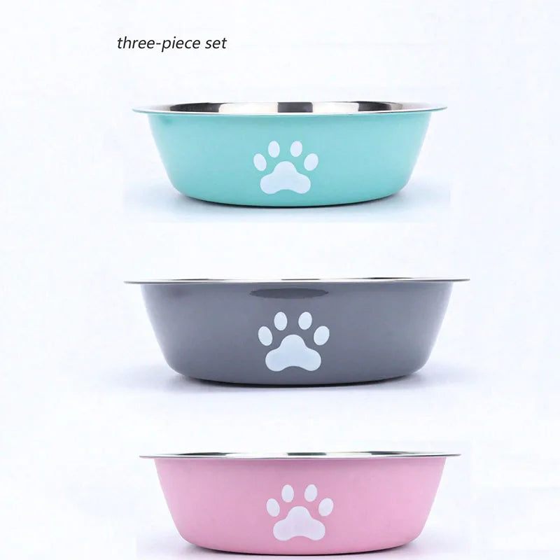 A three-piece set of stainless steel pet bowls in teal, gray, and pink with white paw prints.