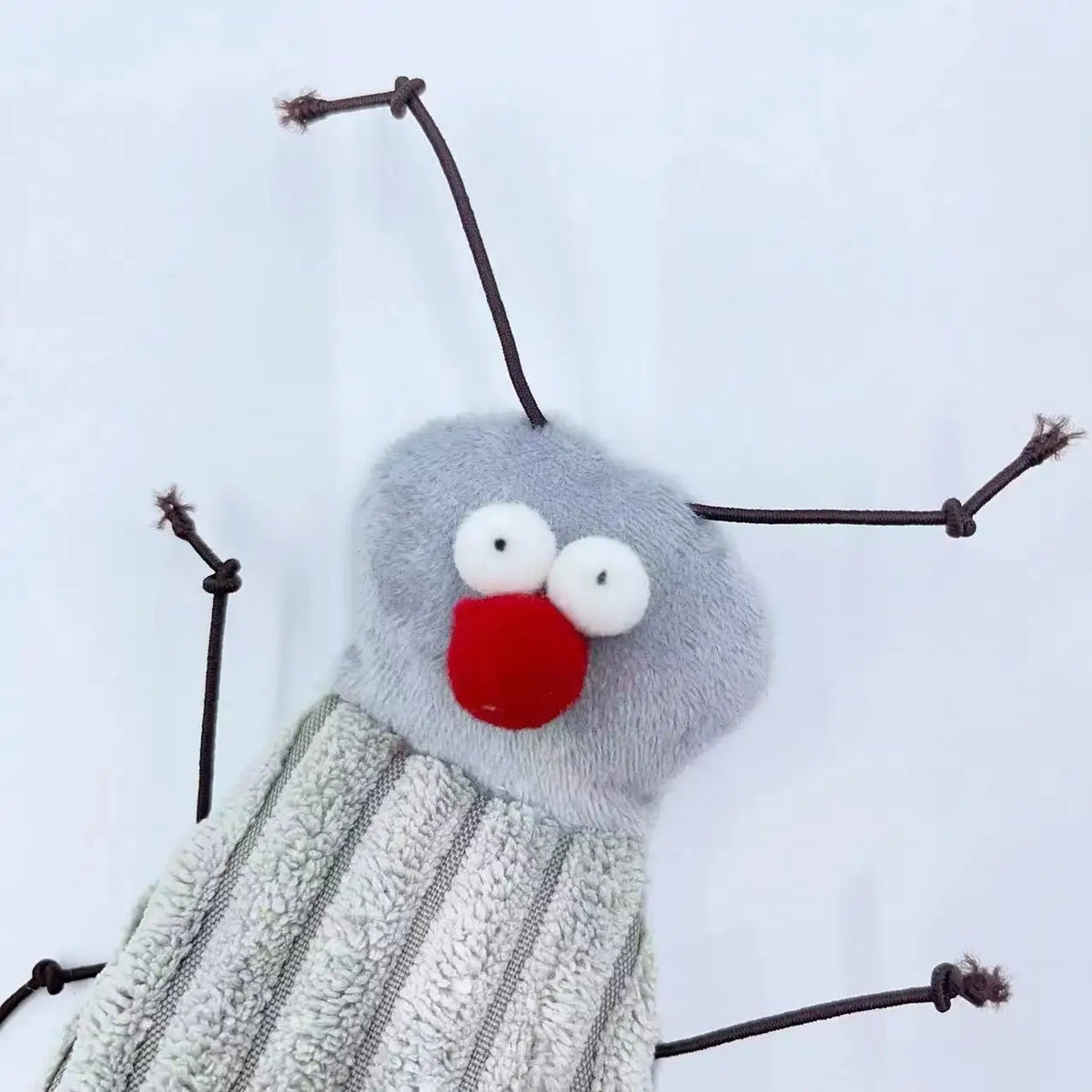 A plush toy resembling a cockroach with large eyes and antennae, featuring gray fur and a red mouth.