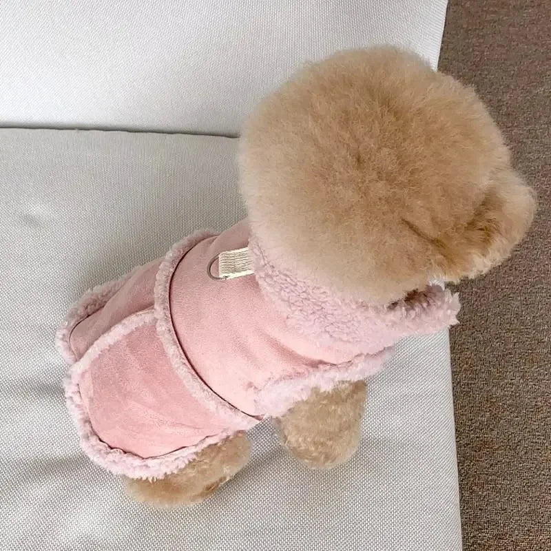 A fluffy, light pink cotton dog vest with a tan face is displayed on a white surface.