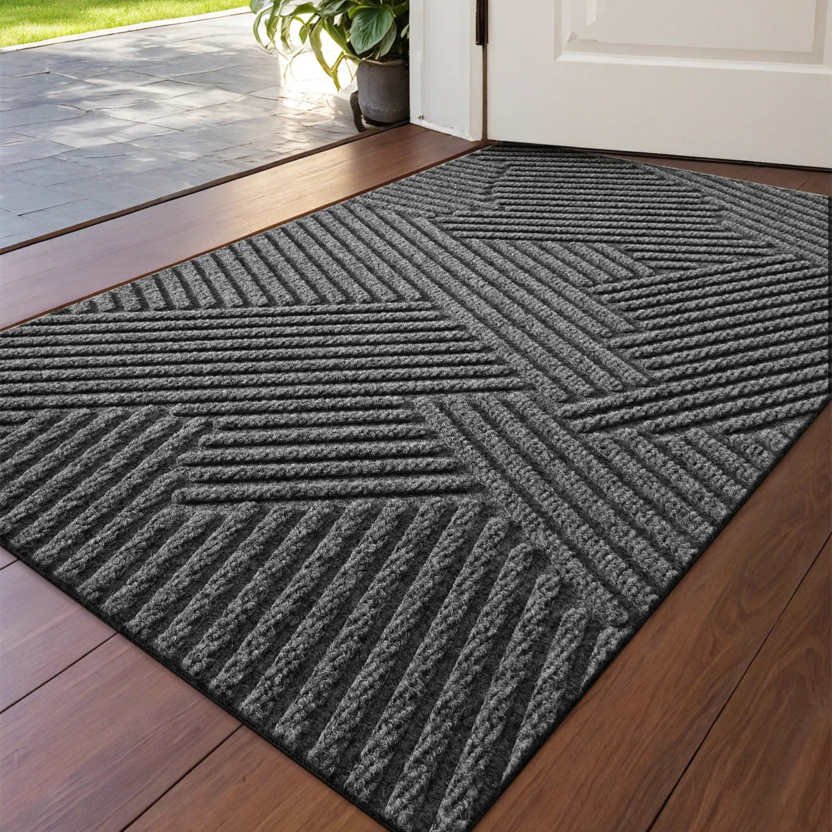 A rectangular gray geometric non-slip doormat placed on a wooden floor.