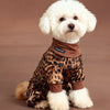 A white poodle wearing a brown leopard print jumpsuit.