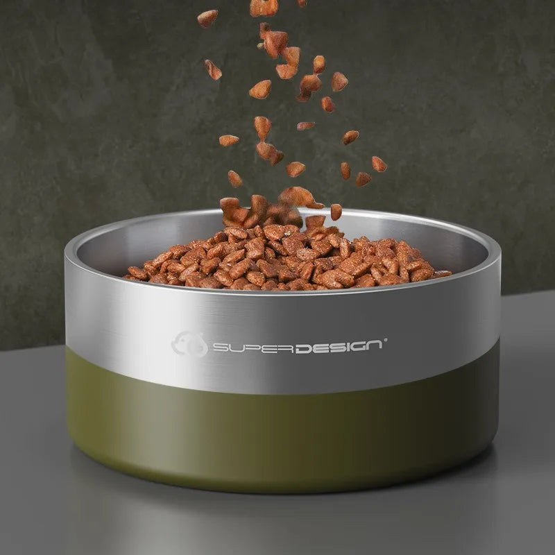 A stainless steel insulated dog bowl with a green base is shown, filled with dry kibble and some pieces are falling out.