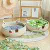A beige woven cat scratcher and comfort bed with green and white fabric and colorful play balls on a light wood floor.