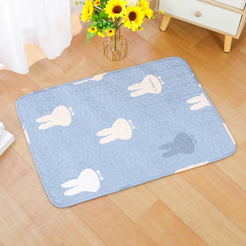 A light blue pet cage mat with a pattern of beige and gray animal shapes placed on a wooden floor.