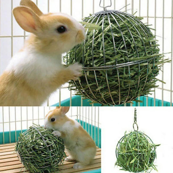 A small rabbit is interacting with a spherical ball made of green foliage, suspended by a metal wire hanger.