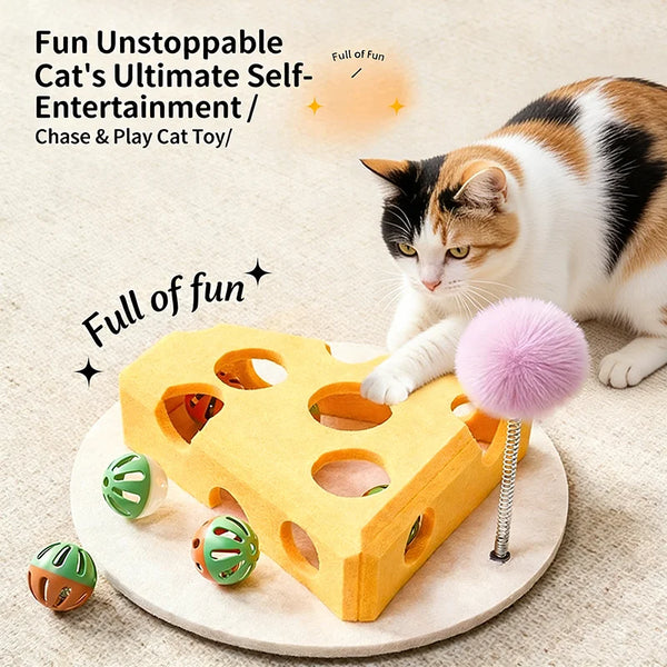 A cat is interacting with a yellow felt maze play box containing small balls and a pink pom-pom toy.