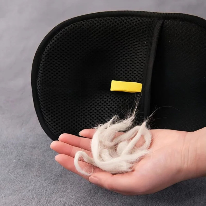 A hand holds a piece of white static-free fluff or lint against a black pet grooming glove.