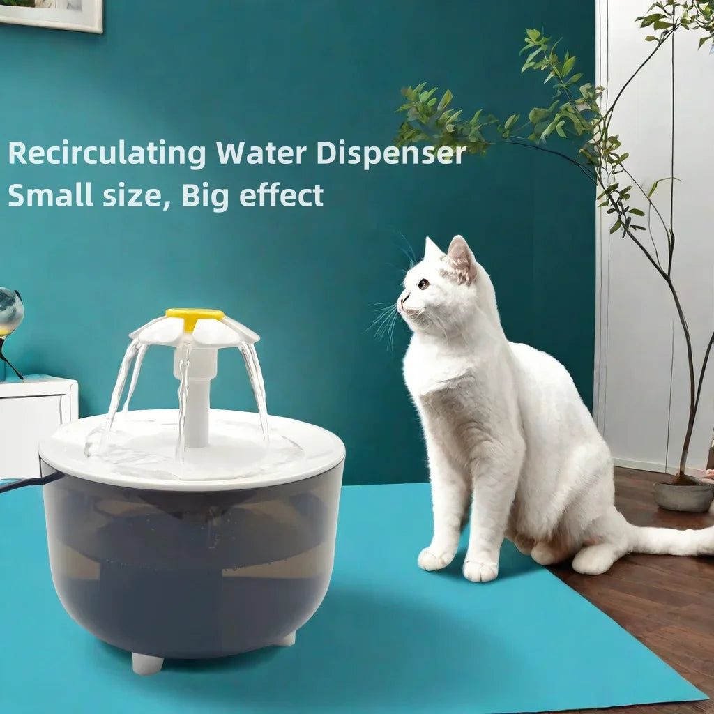 A white cat is looking at a small, gray water dispenser fountain on a blue mat.
