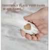 A person's hand gently holds a dog's paw with a heart-shaped file pad on the nail.