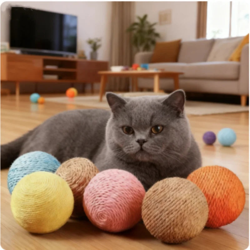 Eine graue Katze liegt inmitten bunteres Sisal-Kratzball auf einem Holzfußboden.