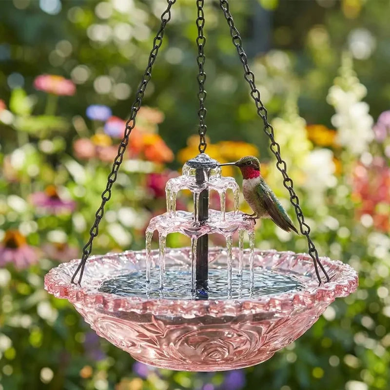 Fontaine d'oiseau solaire à plusieurs niveaux avec un bol en verre rose et un petit oiseau perché sur la structure.