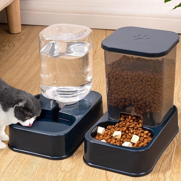 A dark blue automatic pet feeder with an integrated water bowl and a separate compartment for dry food, placed on a wooden fl