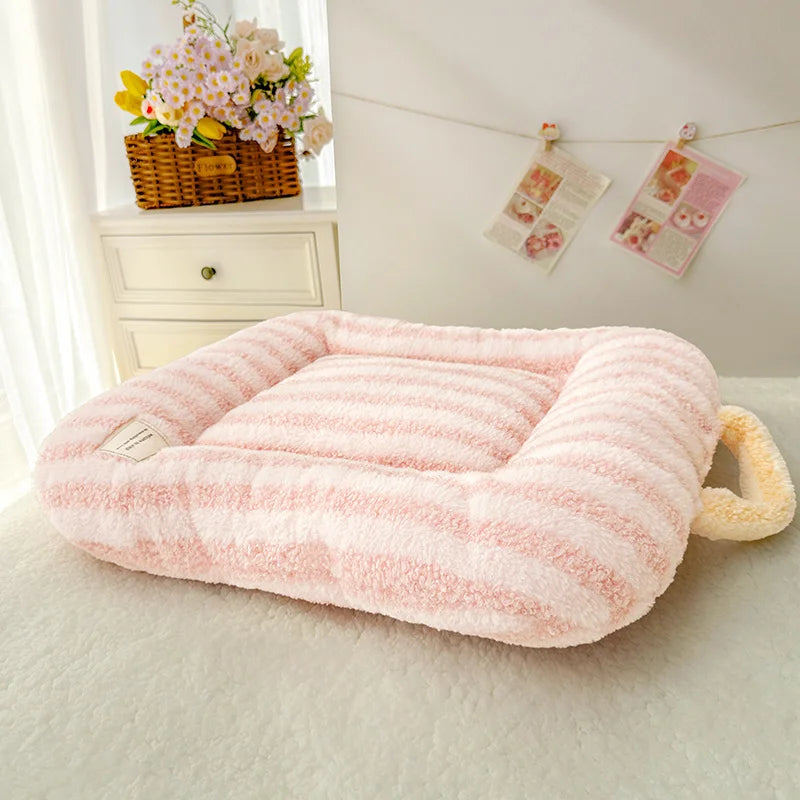 A pink striped plush oval pet bed for cats and small dogs resting on a white surface.