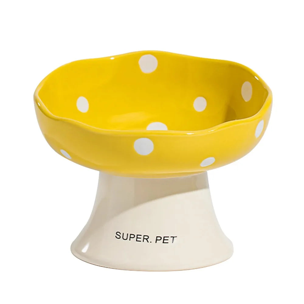 A yellow ceramic pet bowl with white polka dots sits on a light-colored pedestal.