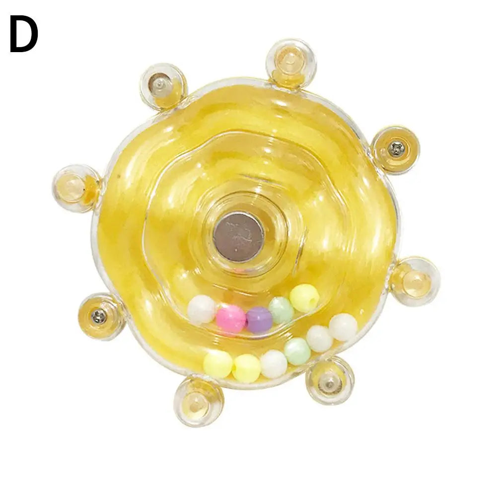 A clear, rotating parrot treat dispenser with a yellow translucent body and colorful beads.