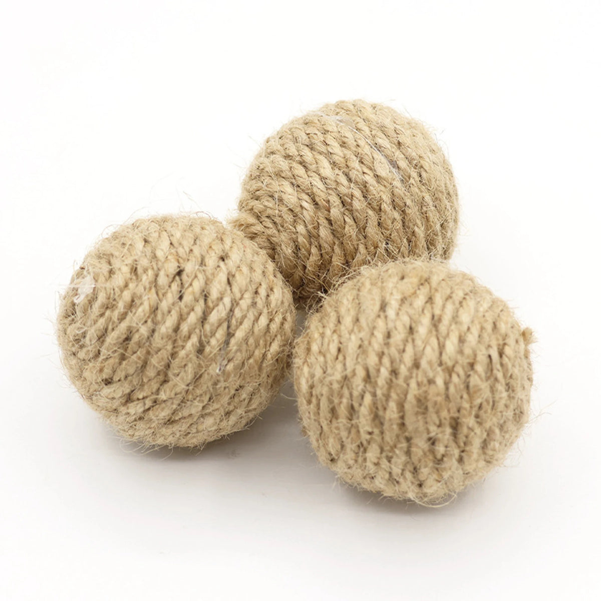 Three balls of handwoven hemp and sisal rope used as cat toys