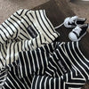 Black and white striped thermal sweater for a small dog lying on a wooden surface.