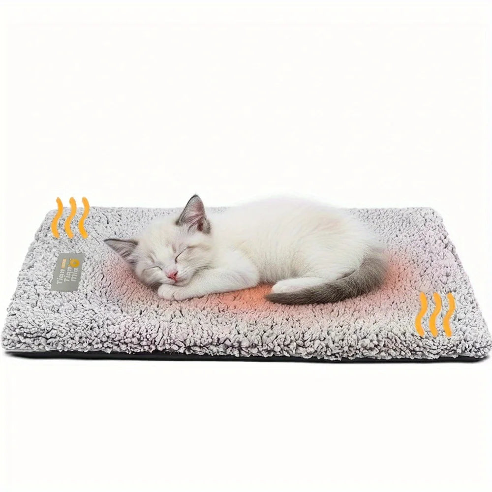 A white cat is resting on a gray, fluffy pet bed mat with orange heat lines visible.
