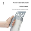A hand is holding a gray integrated pet waste scoop and cleaner with a perforated handle.