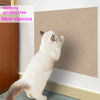 A white cat is using a climbing grinding claw on a beige wall surface.
